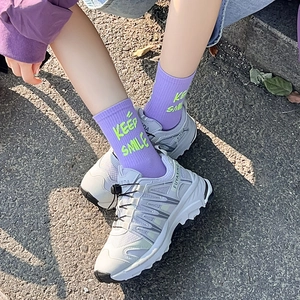 Dettaglio calzini viola con scritte graffiti e sneakers grigie in stile street