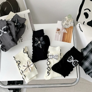 Detail of ruffled cuff socks with 3D ribbon flowers and bows in black, white and grey
