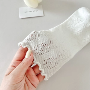 Gros plan de chaussettes en maille blanche avec bords à volants et motifs ajourés chic
