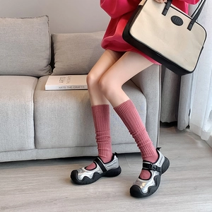 Detalle de zapatillas Mary Jane plateadas con calcetines rosa en un ambiente acogedor