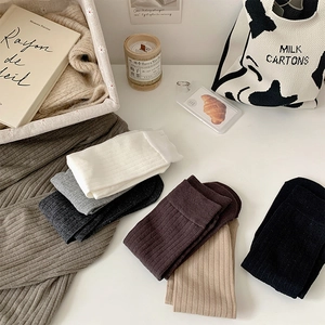 Detail view of multi-color ribbed cotton socks in neutral tones on a cozy white desk