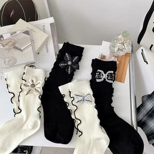 Close-up of frilly trim socks with floral and bow accents in black and beige
