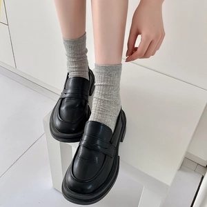 Nahaufnahme schwarzer Plateau-Loafer aus Leder kombiniert mit grauen Zehensocken