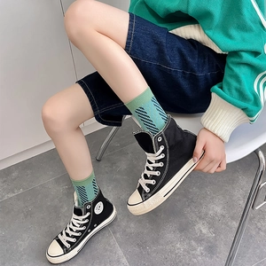 Teal checkered and striped mid-calf socks styled with high-top sneakers and denim shorts