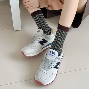 Detail of retro coffee brown striped socks with green diamond pattern on feet