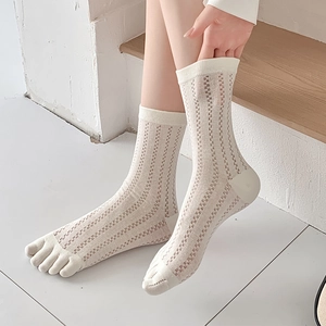 Detail of cream toe socks with vertical mesh knit pattern on model in a soft home setting
