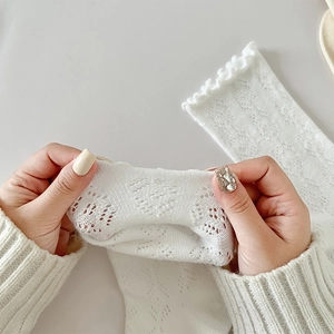 Détail de chaussettes en tricot blanc extensible avec motifs cœurs et bord volanté
