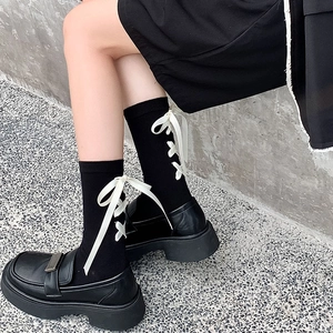 Détail de chaussettes noires style JK avec des nœuds en satin blanc à l'arrière