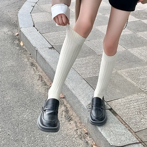 Calcetines altos de canalé blanco crema con mocasines negros de plataforma en la calle