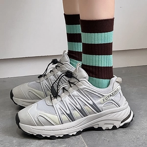 Detail of grey dad sneakers with mesh texture and striped mid-tube casual socks