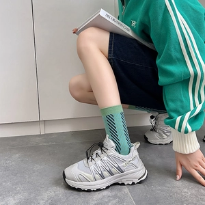 Close-up of grey chunky sneakers paired with striped blue and green crew socks
