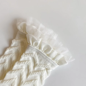 Close-up of white Lolita style socks with ruffled lace trim and woven knit texture