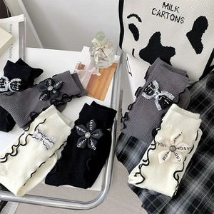 Detail of knit socks with bow and flower charms and delicate ruffle edge trim