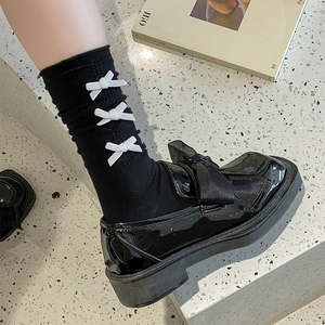 Détail de chaussettes noires à nœuds blancs et mocassins en cuir verni brillant