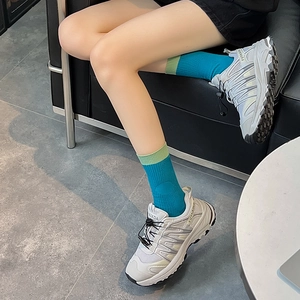Detail of blue and green ribbed socks styled with grey fashion sneakers in modern setting