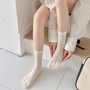 Detail of cream five-toe socks with vertical hollow mesh knit on a wooden surface