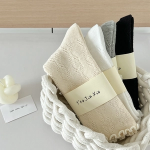 Gros plan sur la maille losange et les bords volantés des chaussettes en coton