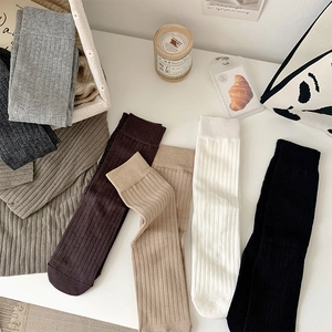 Detailed view of ribbed cotton mid-calf socks in various neutral tones and textures