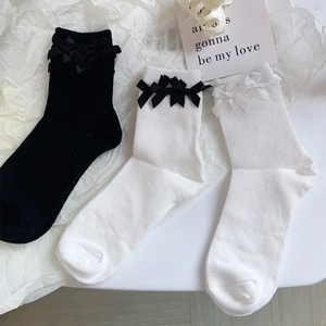 Stesura piatta di calze di cotone con fiocchi decorativi in bianco e nero