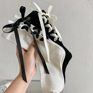 Vue détaillée de chaussettes Lolita noires et blanches avec nœud satiné et laçage