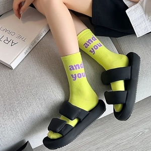 Calze verde fluo con scritte viola abbinate a sandali neri con zeppa in stile street