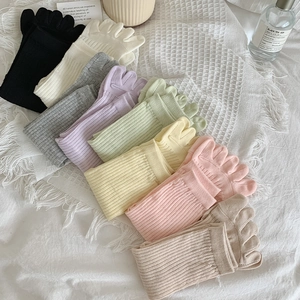 Flache Darstellung von acht bunten Zehensocken in Pastelltönen auf Waffelstoffgewebe