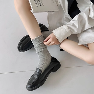 Gros plan de chaussettes grises à volants et résilles avec mocassins en cuir noir