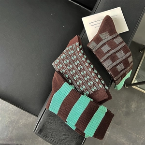Three pairs of vintage brown and green striped cotton socks displayed on leather