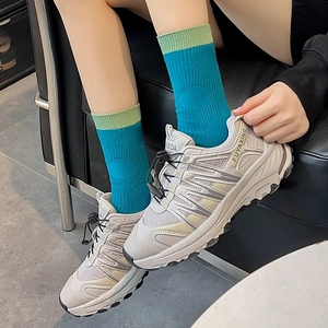 Close-up of off-white chunky mesh sneakers with blue-green patchwork cotton socks