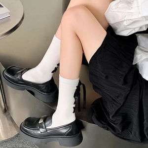 Détail de chaussettes blanches avec nœuds noirs et mocassins à plateforme épaisse