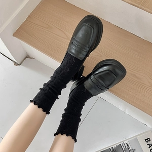 Détail de chaussettes en maille ajourée à bords volantés avec mocassins en cuir noir