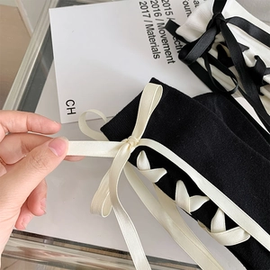 Détail de chaussettes en tricot style JK avec nœud en ruban noir et laçage croisé