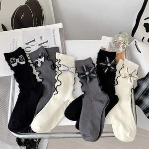 Detail of luxury bow socks in black white and grey with delicate floral accessories