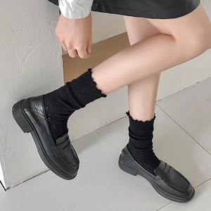 Détail de chaussettes en dentelle noire ajourée portées avec des mocassins en cuir style JK
