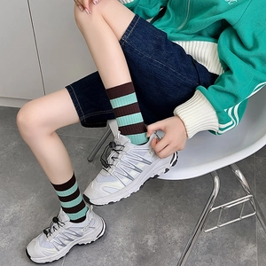 Detail view of brown striped crew socks paired with grey athletic sneakers in street style