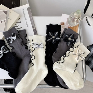 Close-up of bow and floral accents on ruffled cuff socks in black, grey, and cream