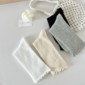 Détail de chaussettes en tricot ajouré quadricolores avec bords à volants en blanc et gris