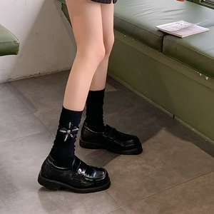 Detail view of black platform loafers paired with bow-print ruffle socks in school style