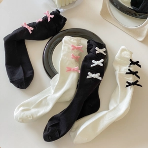 Détail de chaussettes JK avec nœuds en noir et blanc sur une surface minimaliste