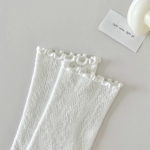 Gros plan de chaussettes blanches en maille pointelle avec bords à volants ajourés