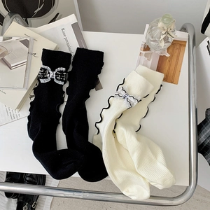 Detail of luxury rib-knit socks with tweed bows and wavy edges in black and cream