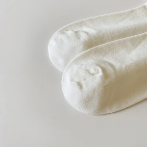 Gros plan de chaussettes en tricot blanc montrant la texture fine et le talon sans couture