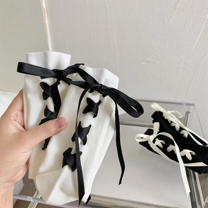 Détail de chaussettes mi-mollet style JK avec rubans lacés et nœuds en noir et blanc