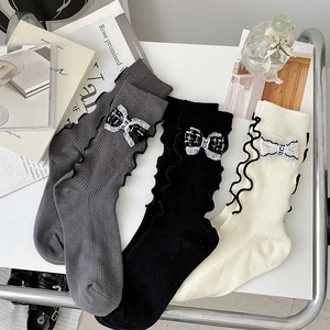 Detail of ruffled trim and plaid bowknot with CE letter print on ribbed knit socks