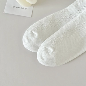 Détail rapproché de chaussettes blanches en maille ajourée avec motifs losanges