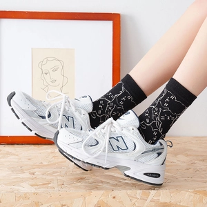 Close-up of black mid-calf socks featuring cute white cat patterns with retro sneakers