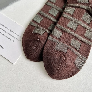 Close-up of coffee brown knit socks featuring silver metallic thread geometric check pattern