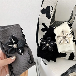 Close-up of knit socks with wavy edges, ribbon bows and vintage metallic buttons