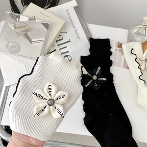 Close-up of ribbed cotton socks with floral detail, metal button and ruffle trim