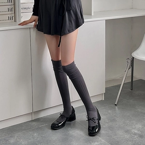 Detail of dark grey over-knee socks with vertical stripes paired with Mary Jane shoes